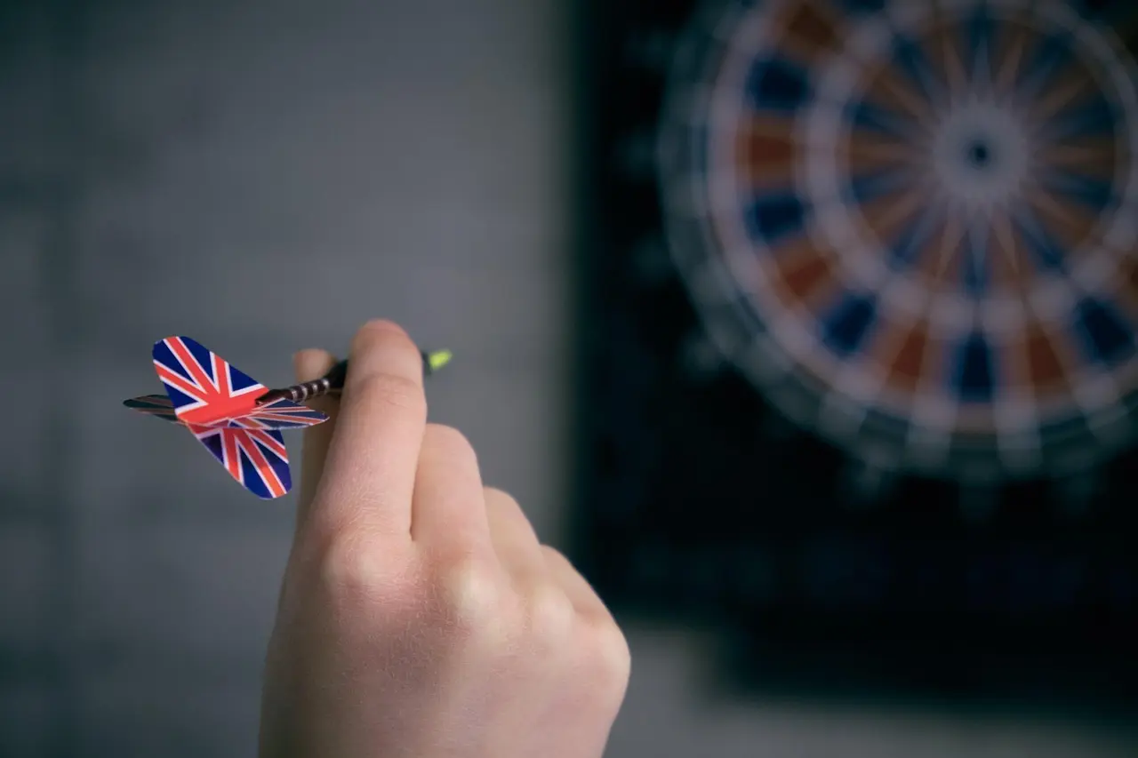 Hånd med dartpil foran dartskive